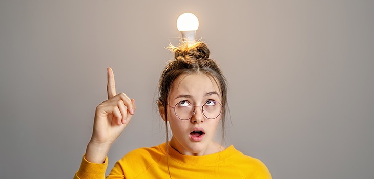 Menina de óculos, com uma lampada acessa em cima da cabeça, representando ideia. 
